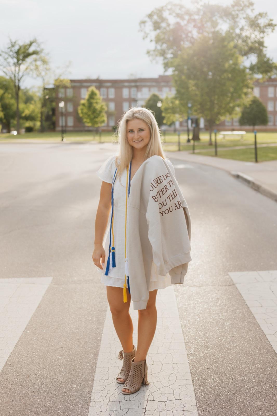 Abigail holding a Senti hoodie on graduation day